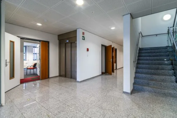 Hal met trap, lift en open deuren in een kantoorgebouw aan de Lange Dreef.